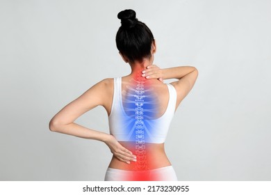 Woman suffering from pain in back on light background - Shutterstock ID 2173230955