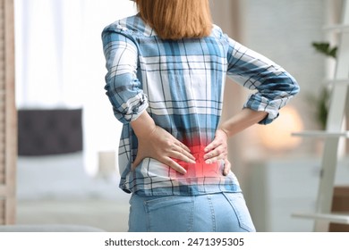 Woman suffering from pain in lower back at home, closeup - Powered by Shutterstock