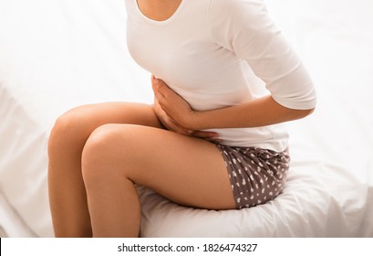 Woman Suffering From Stomach Pain, Sitting On Bed. Abdominal Bloating, Intestinal Gas