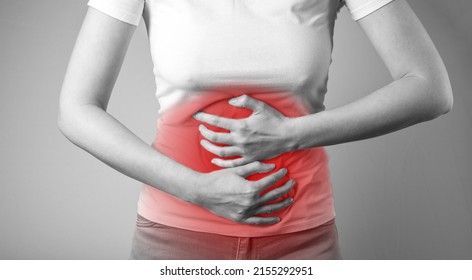 Woman Suffering From Stomachache. Abdominal Pain Caused By Inflammation, Injury, Disease. Female Holding Stomach With Red Spot. Black And White. High Quality Photo