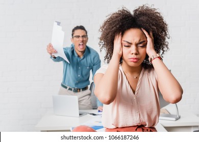 Woman suffering from stress because of angry male colleague in office