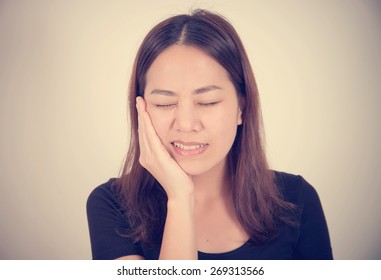 Woman Suffering Toothache With Hand On Face Isolated On A White Background With Vintage Filter Effect 