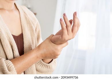 woman suffering from wrist pain, numbness, or Carpal tunnel syndrome hand holding her ache joint  - Shutterstock ID 2093499736