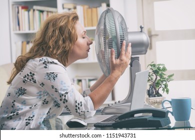 Woman Suffers From Heat While Working In The Office And Tries To Cool Off By The Fan