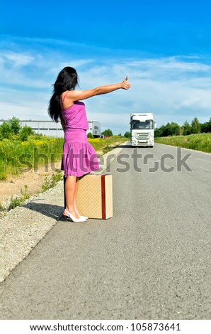 Woman with suitcase hitchhiking a car