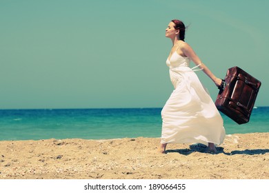 woman with suitcase on the beach. Photo in old image style.
