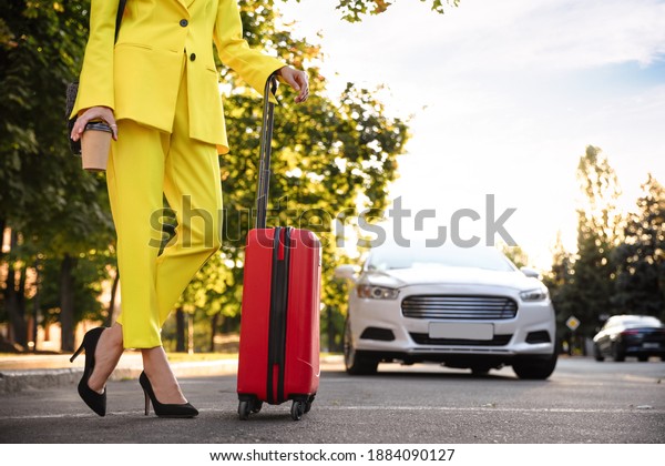 Woman with suitcase waiting for taxi on city\
street, closeup