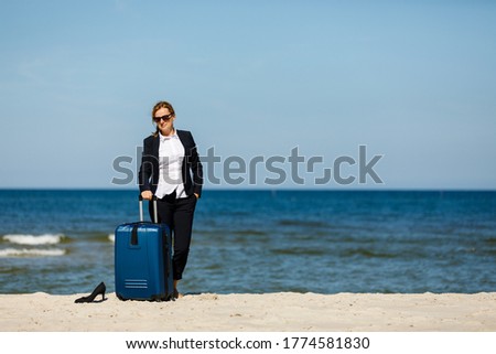Woman with suitcase walking on beach