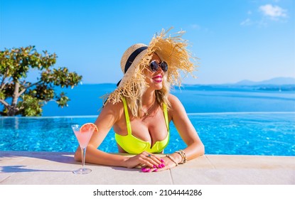 Woman in summer hat enjoying cocktail by the pool