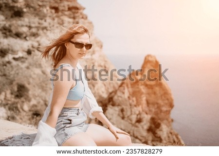Woman summer travel sea. Happy tourist in sunglasses enjoy taking picture outdoors for memories. Woman traveler posing on beach at sea surrounded by volcanic rocks, sharing travel adventure journey