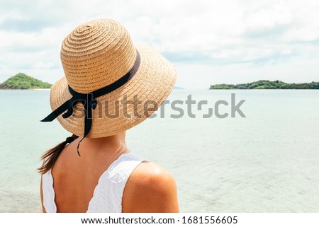 Woman in summer vacation wearing straw hat enjoying the view at the ocean