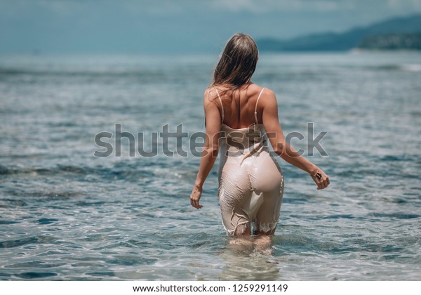 Woman in summer  white dress standing in the sea.Sporty Big ass. Back View. Phuket. Thailand