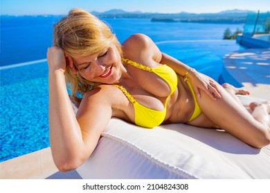 Woman sunbathing by the infinity pool with beautiful sea view in background