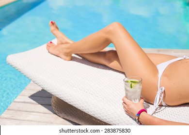 Woman Sunbathing By The Pool With Glass Of Refreshing Cold Drink