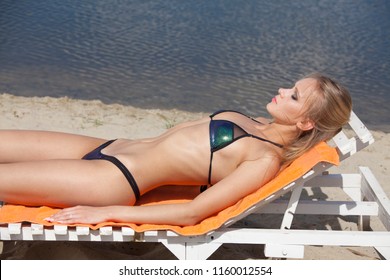 Woman sunbathing on the beach, sleeping on the sun chair