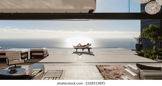 Woman sunbathing on lounge chair at poolside overlooking ocean - Shutterstock ID 2328313895