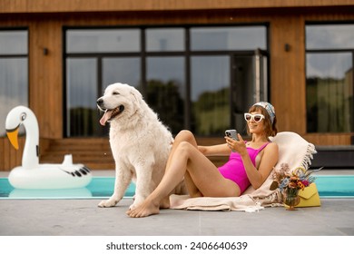 Woman sunbathing while relaxing with her dog near house with a swimming pool. Friendship with pets and summer vacation concept - Powered by Shutterstock