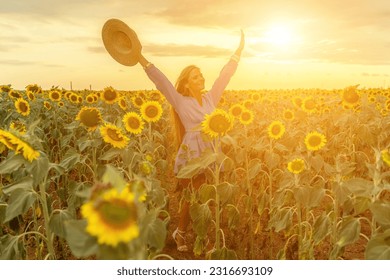 Woman sunflower field. Happy girl in blue dress and straw hat posing in a vast field of sunflowers at sunset. Summer time. - Powered by Shutterstock