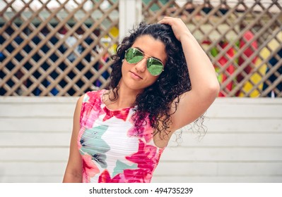 Woman With Sunglasses Looking At Camera Over Garden Fence