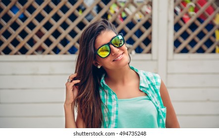 Woman With Sunglasses Looking At Camera Over Garden Fence