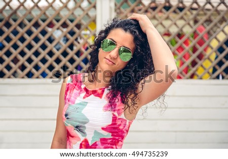 Woman with sunglasses looking at camera over garden fence