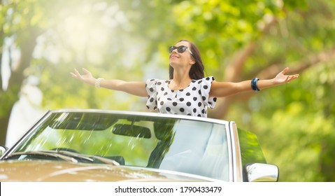 Woman In Sunglasses Sits On Top Of The Convertible, Arms Wide Open, Soaking Up The Sun And Fresh Air.