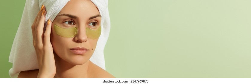 Woman In Sunlight With Eye Patches On Pastel Green Background. Morning Skincare Routine