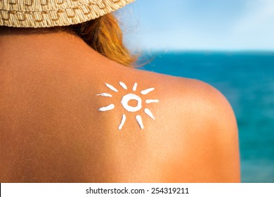 Woman With Suntan Lotion At The Beach In Form Of The Sun, Skin Care And Protection