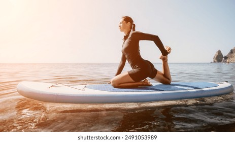 Woman sup yoga. Happy sporty woman practising yoga pilates on paddle sup surfboard. Female stretching doing workout on sea water. Modern individual female hipster outdoor summer sport activity.