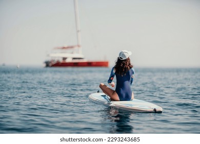 Woman sup yoga. Middle age sporty woman practising yoga pilates on paddle sup surfboard. Female stretching doing workout on sea water. Modern individual female hipster outdoor summer sport activity. - Powered by Shutterstock