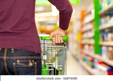 Woman in a supermarket running trough the aisle with a shopping cart