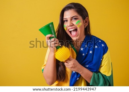 Woman supporter of Brazil, soccer championship, using brazil flag as cover. honking and partying at football match. Horn.