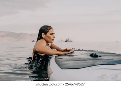 Woman Surfboard Ocean - A woman in a black swimsuit is in the ocean on a surfboard, looking out at the water. - Powered by Shutterstock