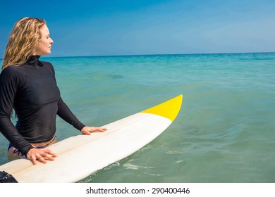 Woman with a surfboard on a sunny day at the beach