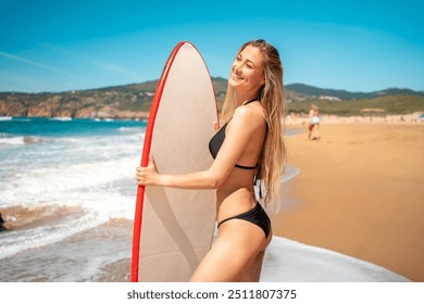 Woman surfer standing with surfboard at beach. Female surfer in bikini posing with surfboard near ocean. Surfgirl standing at water edge ready for surfing on sunny day. - Powered by Shutterstock