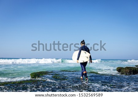Woman surfer with surfboard going to surf at seaside