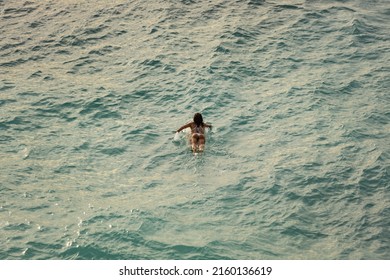 Woman surfer, view from the cliff in Uluwatu beach, Bali