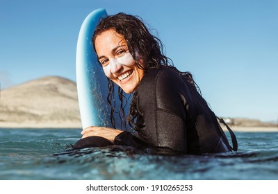 Woman surfing in the sea with a yellow surfboard - Sportive girl surfing in the Atlantic ocean, on a sunny day with blue sky and transparent waves - Powered by Shutterstock