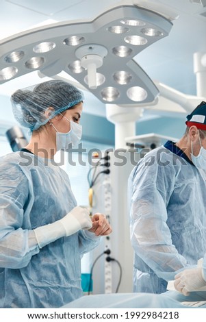 Woman surgeon close-up, at the operating room table with a team of colleagues preparing for the operation Saving lives, modern surgery