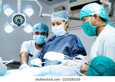 Woman Surgeon With Supporting Practitioners Busy Doing Surgery At Operating Room - Concept Of Teamwork, Healthcare Treatment And Woman Empowerment.