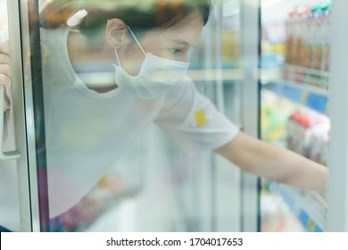 Woman With The Surgical Mask And Gloves, Looking For The Drinks, In Beverage Cooler In Grocery Shop After Coronavirus Pandemic.Shot Through Glass