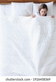 Woman In Surprise Looking Under Blanket In Bed Top View. Heavy Menstruation Concept