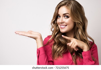 Woman surprise showing product .Beautiful girl  with curly hairstyle  pointing to the side . Presenting your product.  Expressive facial expressions emotions  businesswoman or clerk
,