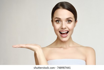 Woman surprise showing product .Beautiful girl  expressive  pointing to the side . Presenting your product. . Expressive facial expressions