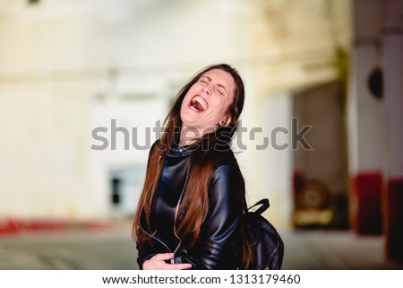 Woman surprised by a joke laughing to noisy laughter, opening her mouth widely.