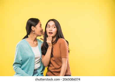 woman surprised when her friend talks whispering in her ear with copyspace - Shutterstock ID 2065086074
