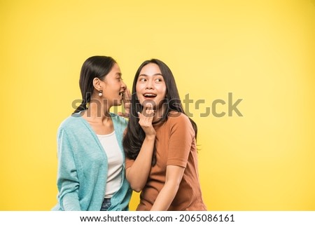 woman surprised when her friend talks whispering in her ear with copyspace
