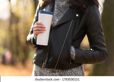 Woman in sweater and leather jacket holding a reusable tumbler of coffee or tea. Zero waste. Eco friendly concept.