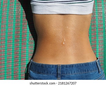 Woman With A Sweaty Back Laying On A Picnic Mat In The Hot Sunshine.