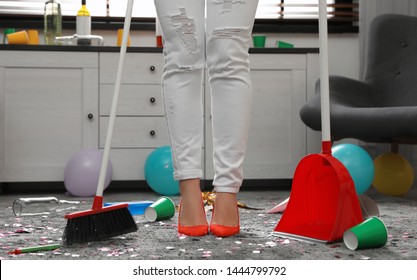 Woman With Sweep Broom And Dust Pan Cleaning Messy Room After Party, Closeup View Of Legs